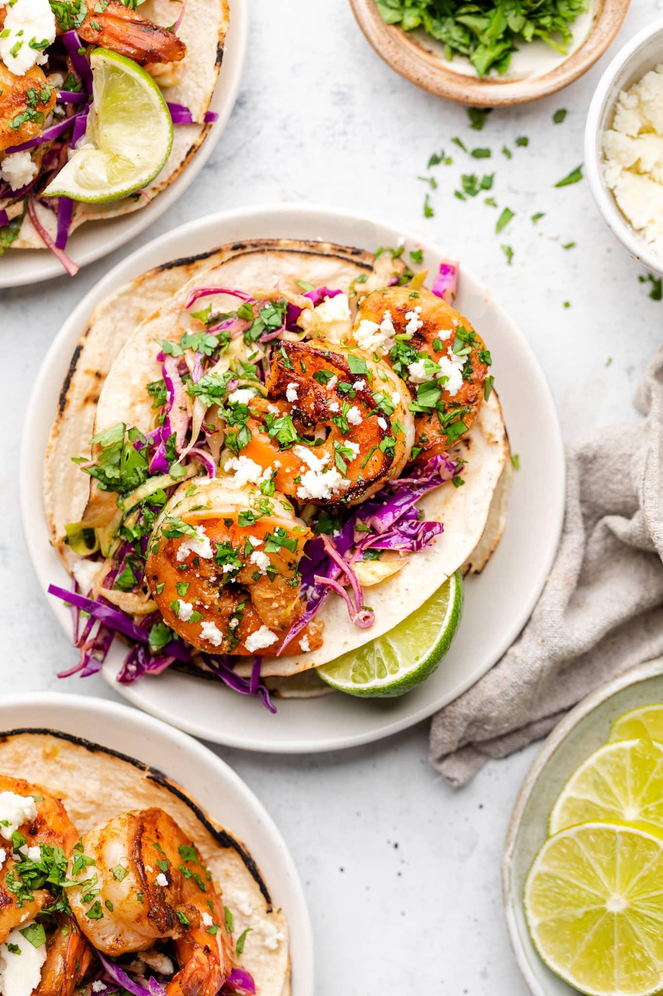 Overhead shot of assembling chipotle shrimp tacos with cabbage slaw and toppings
