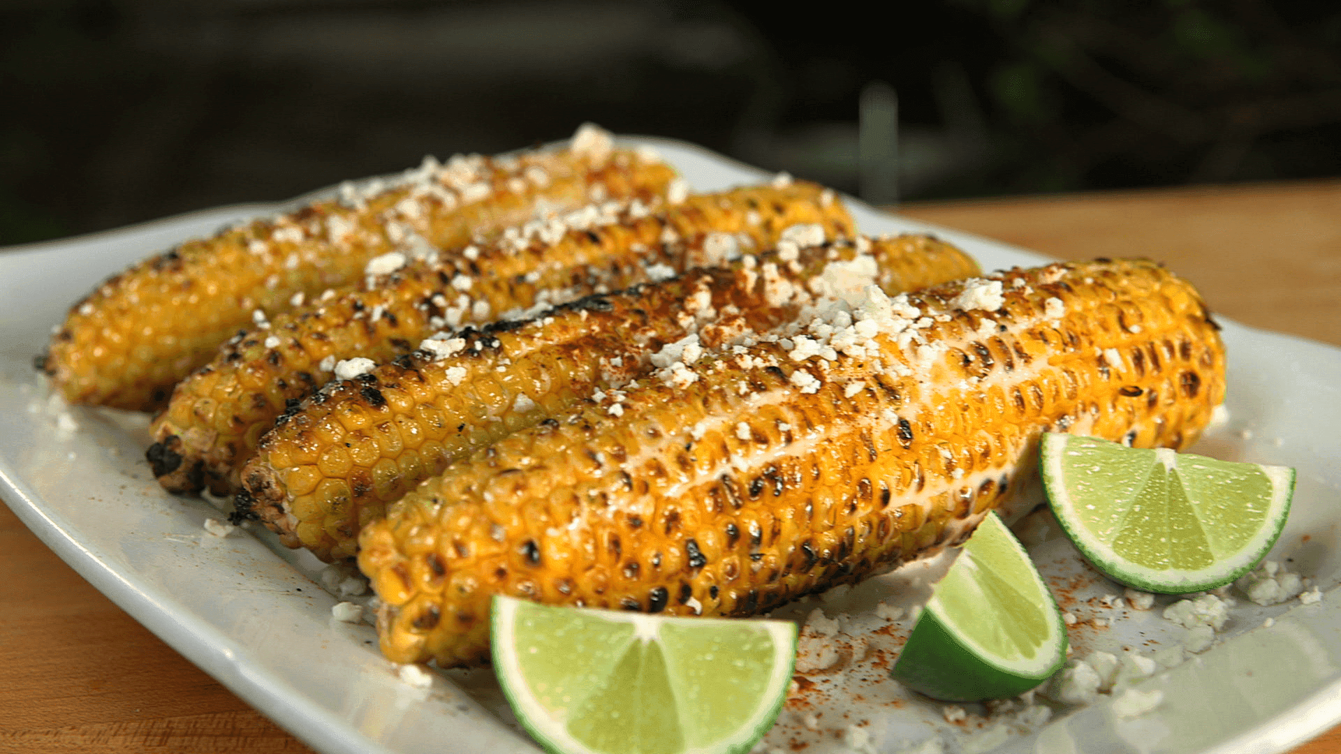 Close-up of grilled corn being prepared for elote