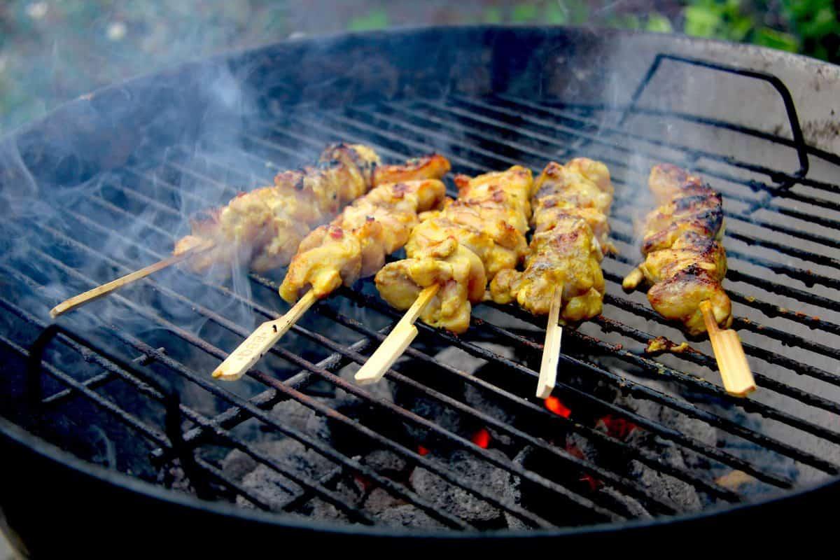 chicken satay skewers being grilled over charcoal