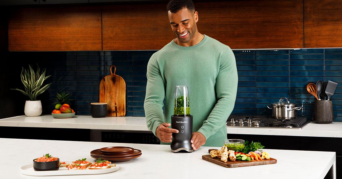 person blending a green smoothie in a kitchen