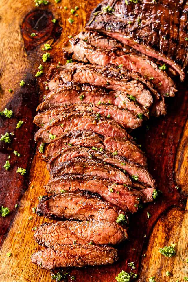 raw flank steak being marinated with garlic and herbs