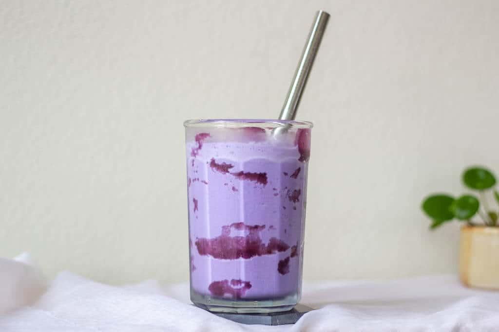 a glass of ube milkshake with a straw