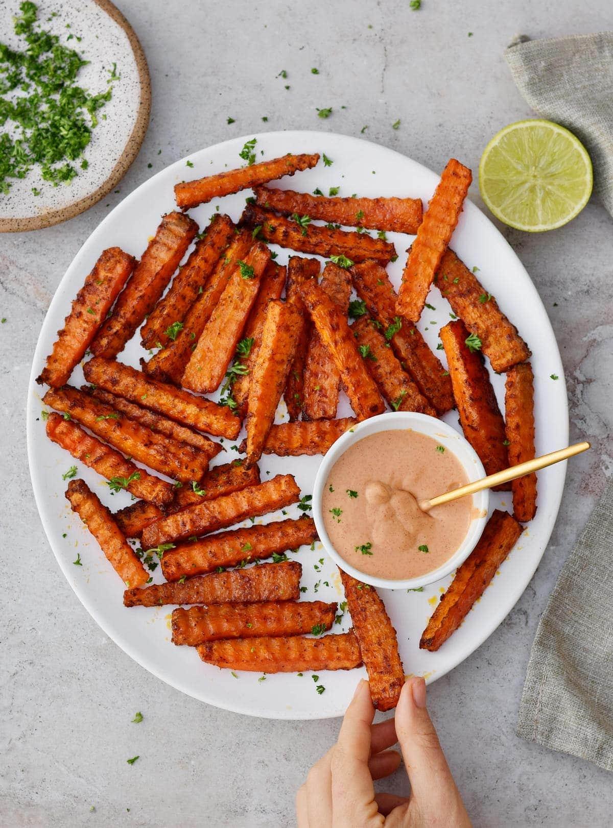 A hand reaching for Blackberry Sage Carrot Fries