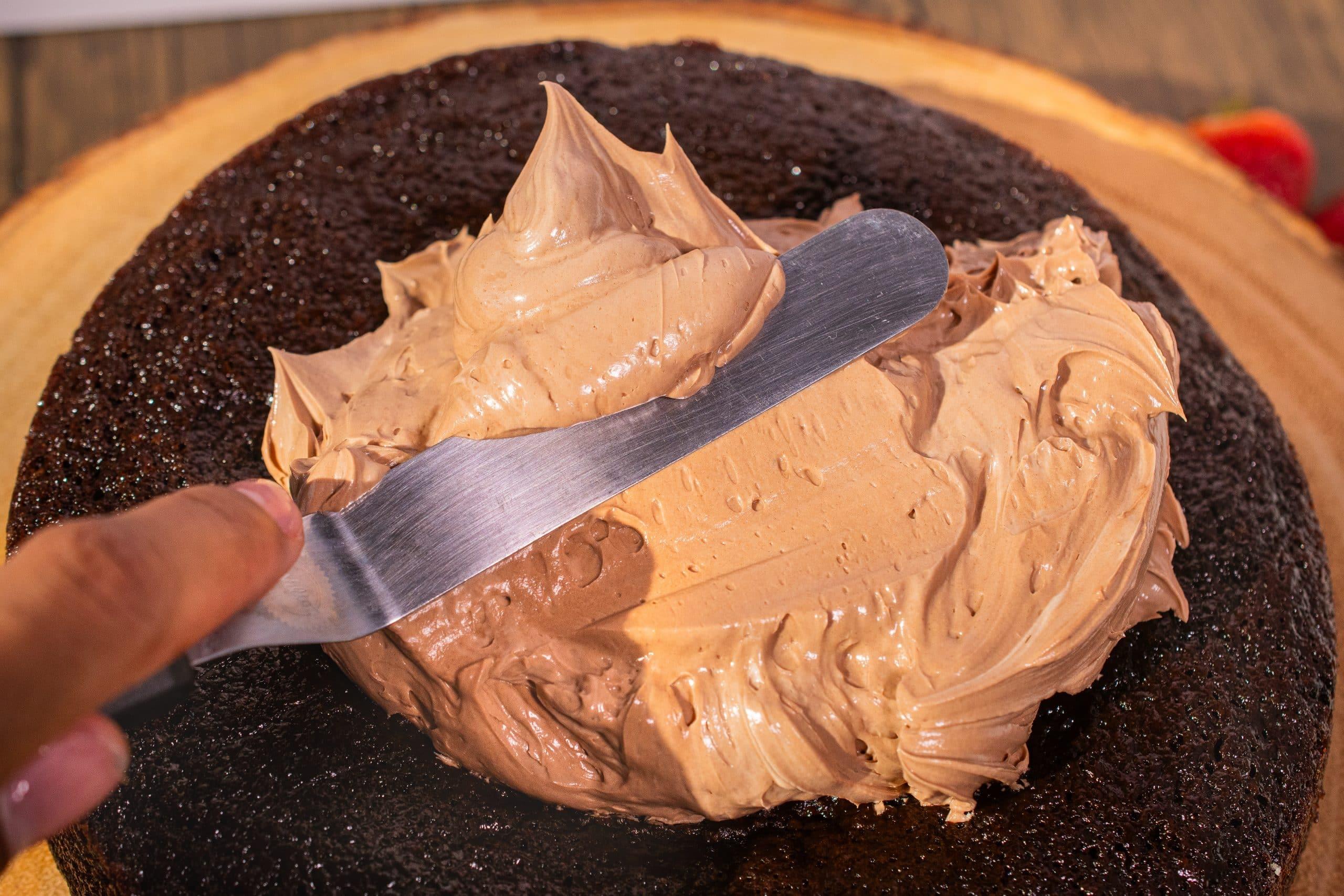 chocolate buttercream being spread on a cake layer
