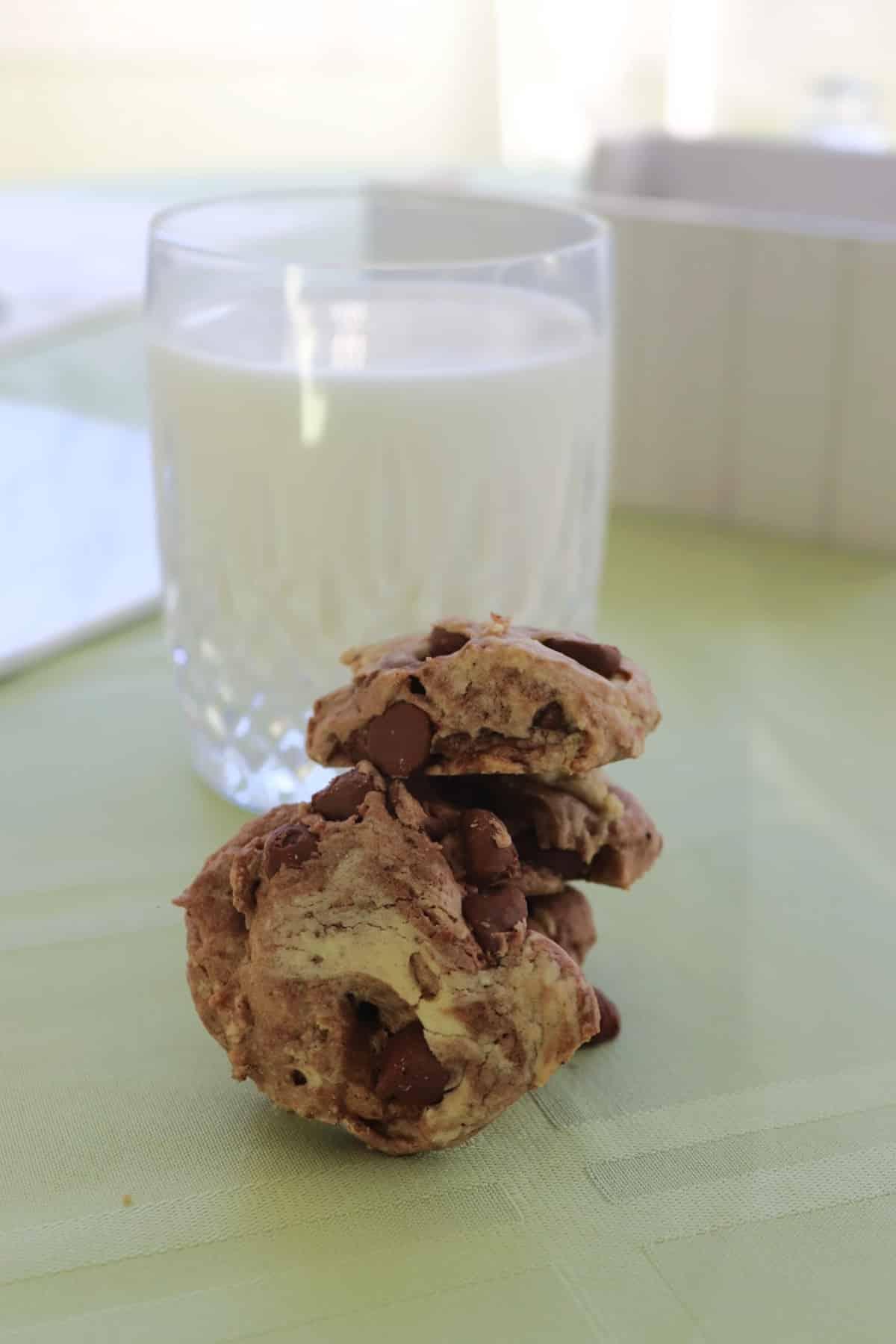 A close-up of a stack of chewy chocolate marble cookies with a glass of milk