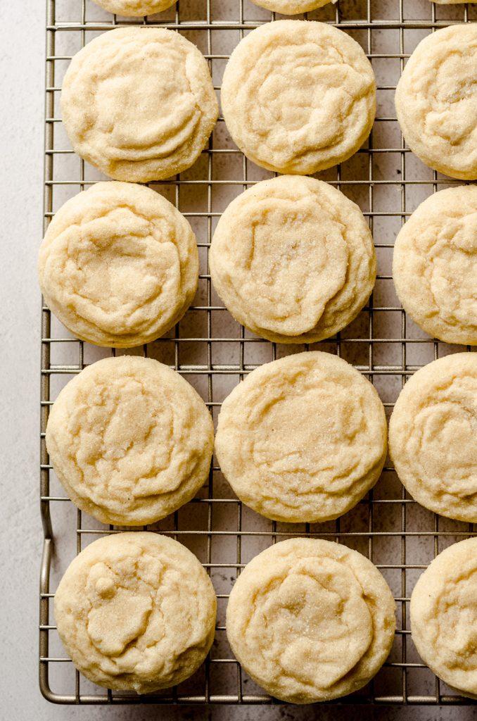 overhead shot of baked vanilla bean sugar cookies on a cooling rack, with visible vanilla specks