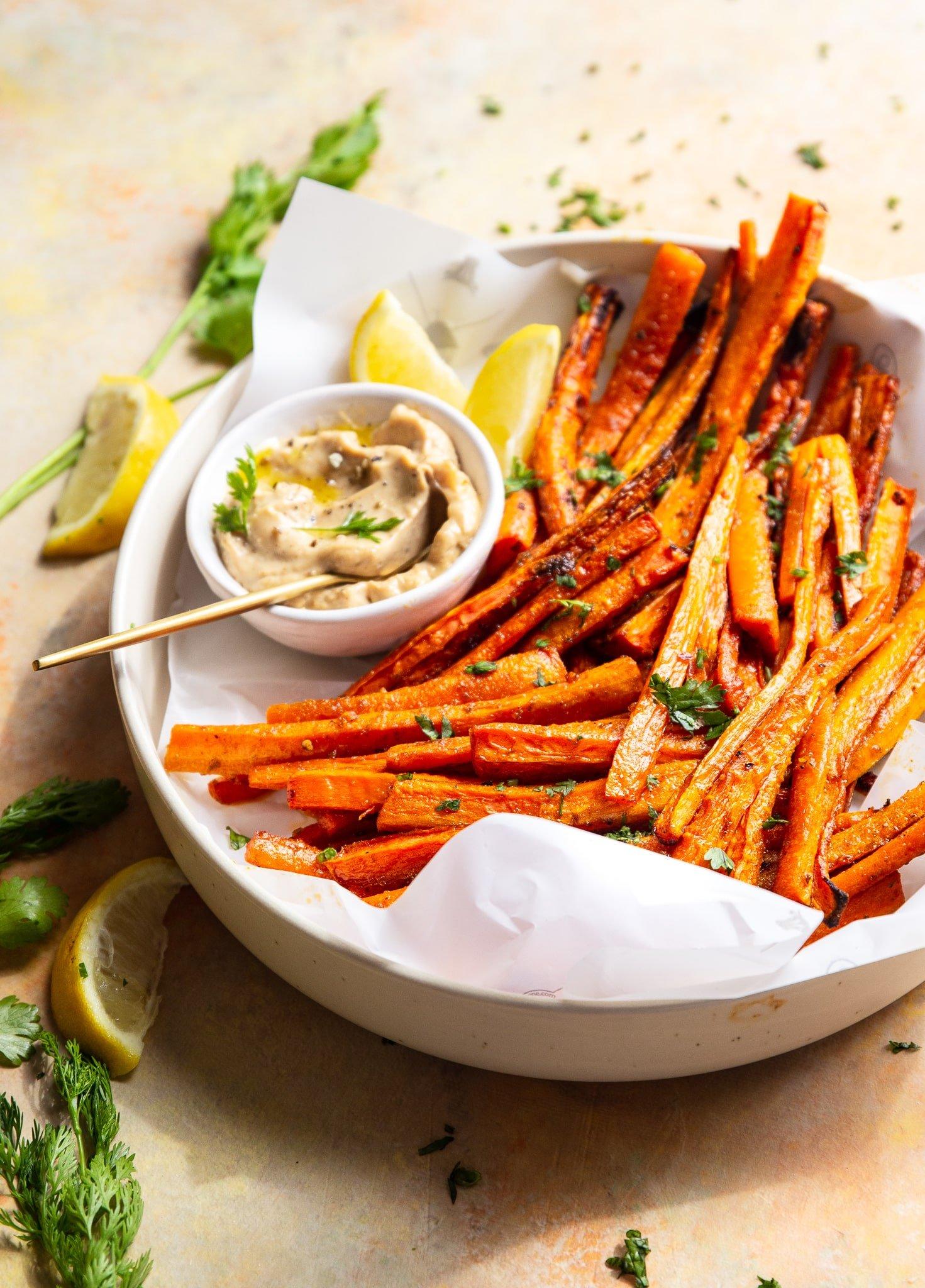 close up of a bowl of lemon pepper roasted carrot fries on a picnic blanket
