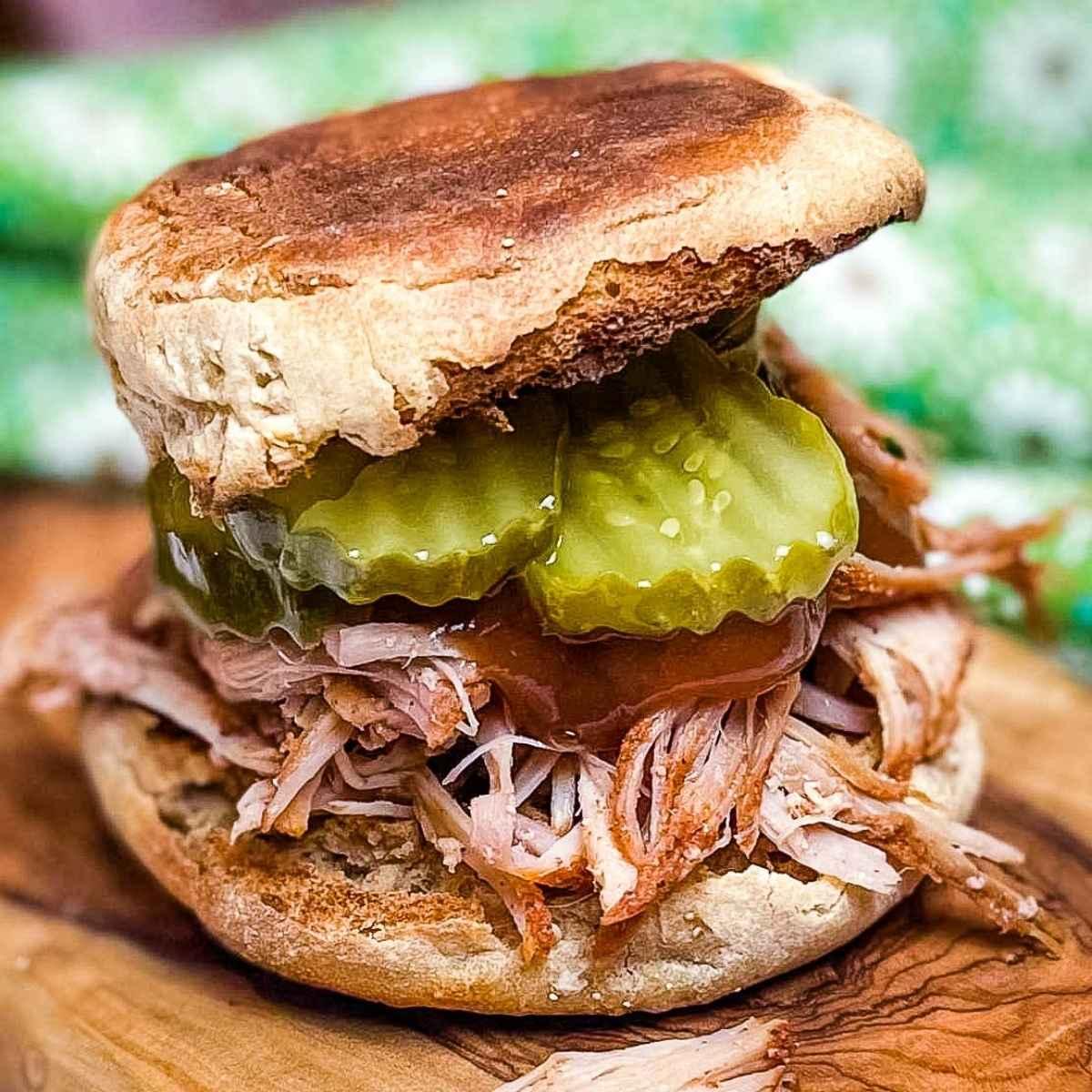 mouthwatering pulled pork sandwich on a rustic wooden board, slow cooker in background, natural lighting