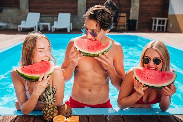 a group of friends laughing and enjoying watermelon mint virgin mojitos by the pool