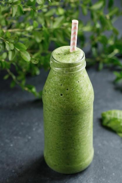 a close-up of a green smoothie being poured into a glass from a blender