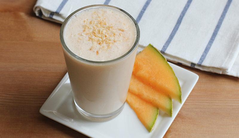 a blender with cantaloupe and coconut being blended