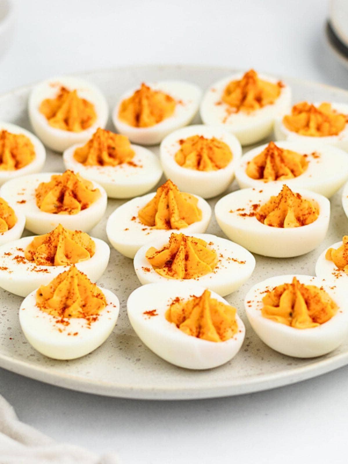 platter of classic deviled eggs with creamy mustard filling and paprika garnish, soft lighting