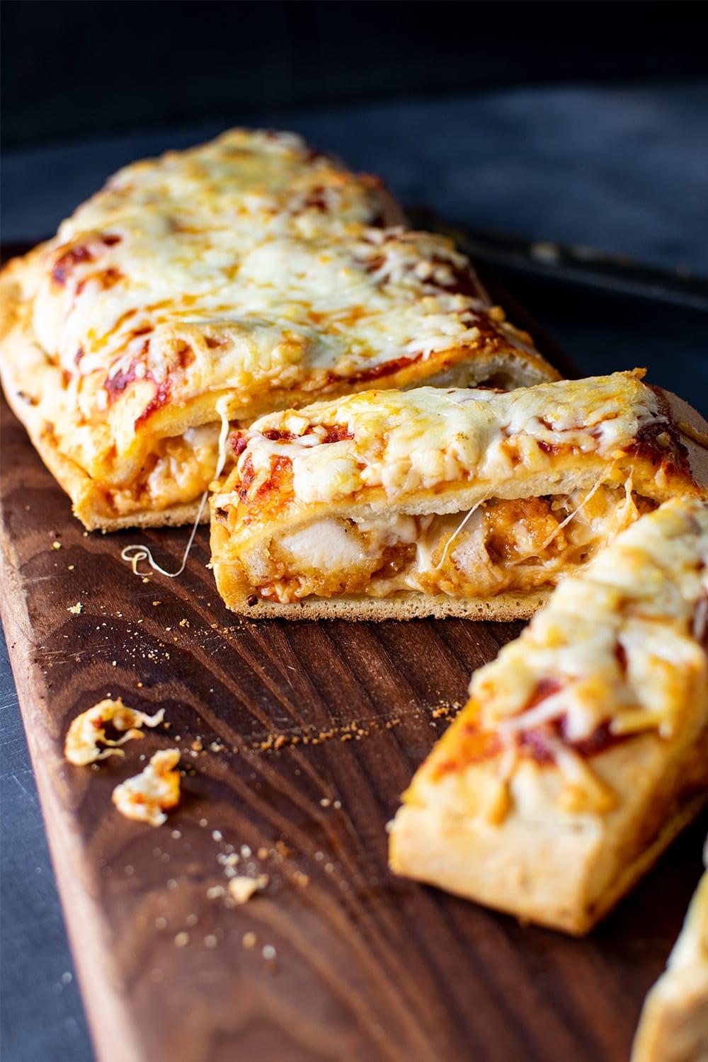 close up shot of a golden brown chicken parmesan calzone cut open with melted cheese oozing out