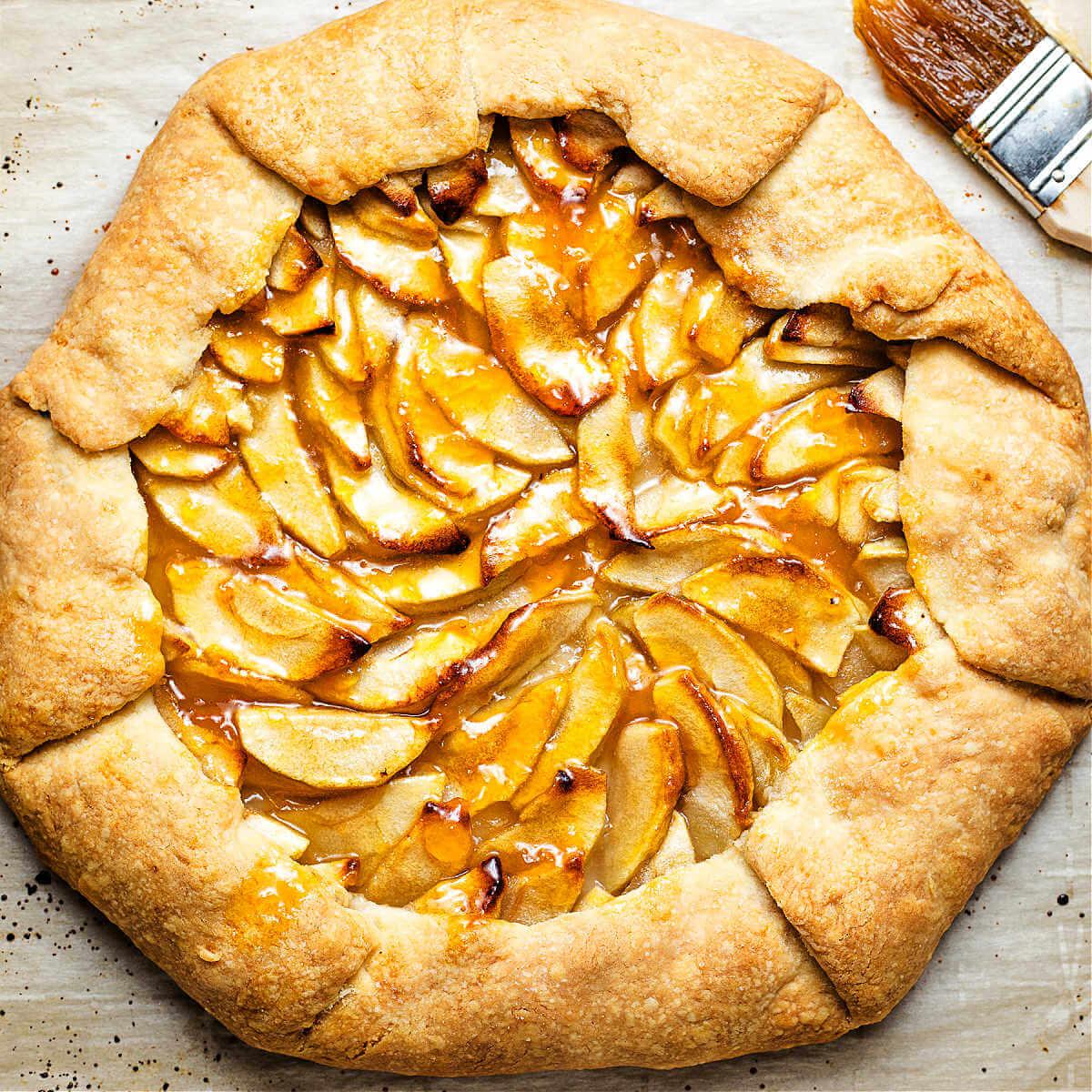 rustic kitchen scene with a person arranging sliced apples in a tart pan