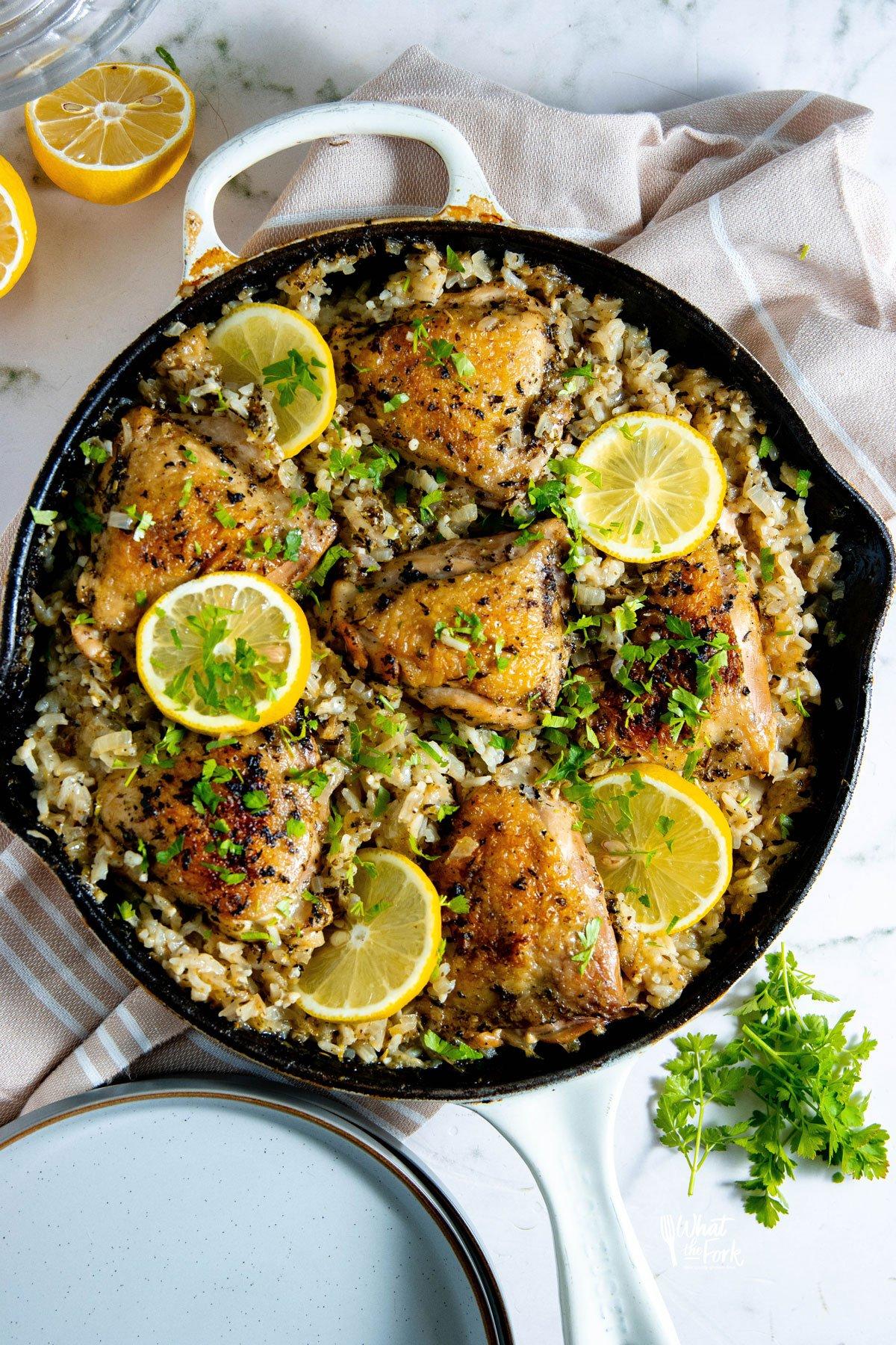 Rustic lemon herb chicken and rice in a cast iron skillet, garnished with fresh parsley
