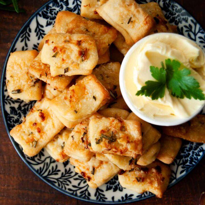 platter of golden crispy baked parmesan cheese bites with fresh herbs and dipping sauce