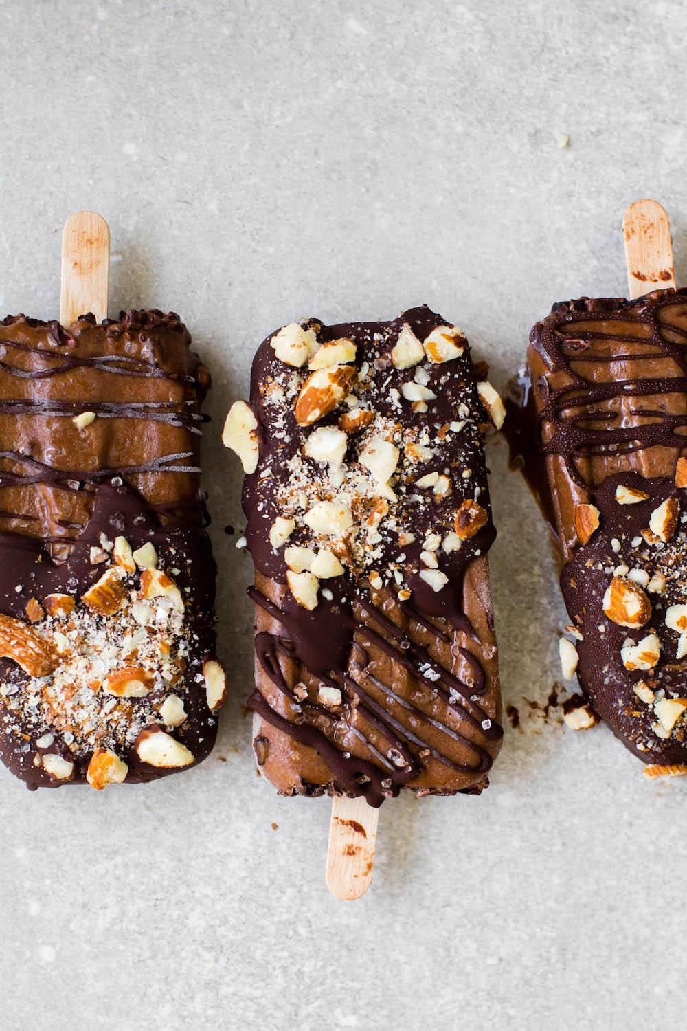 a close-up shot of a person sprinkling sea salt on a dark chocolate popsicle