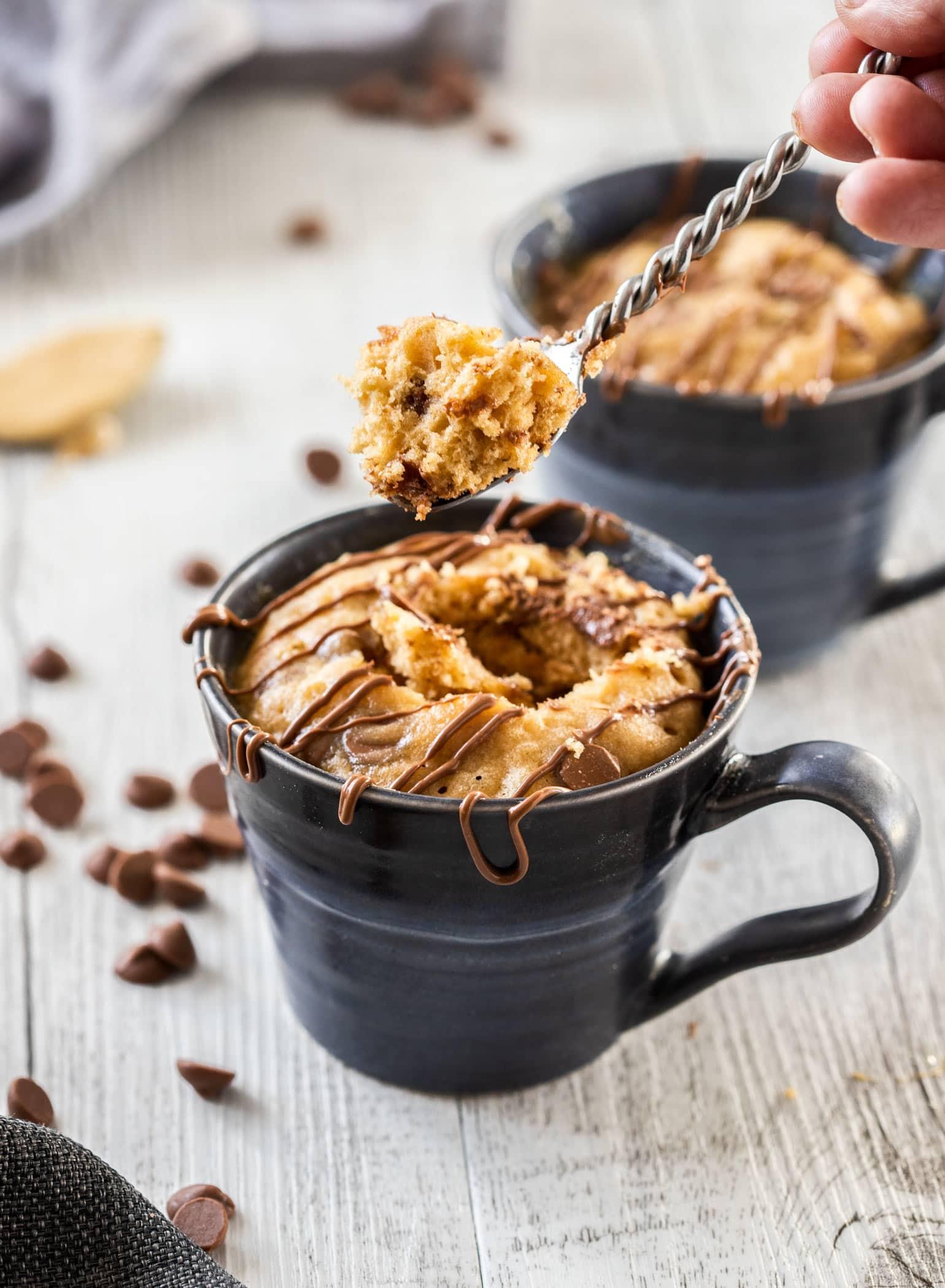 peanut butter fudge mug cake being stirred in a mug