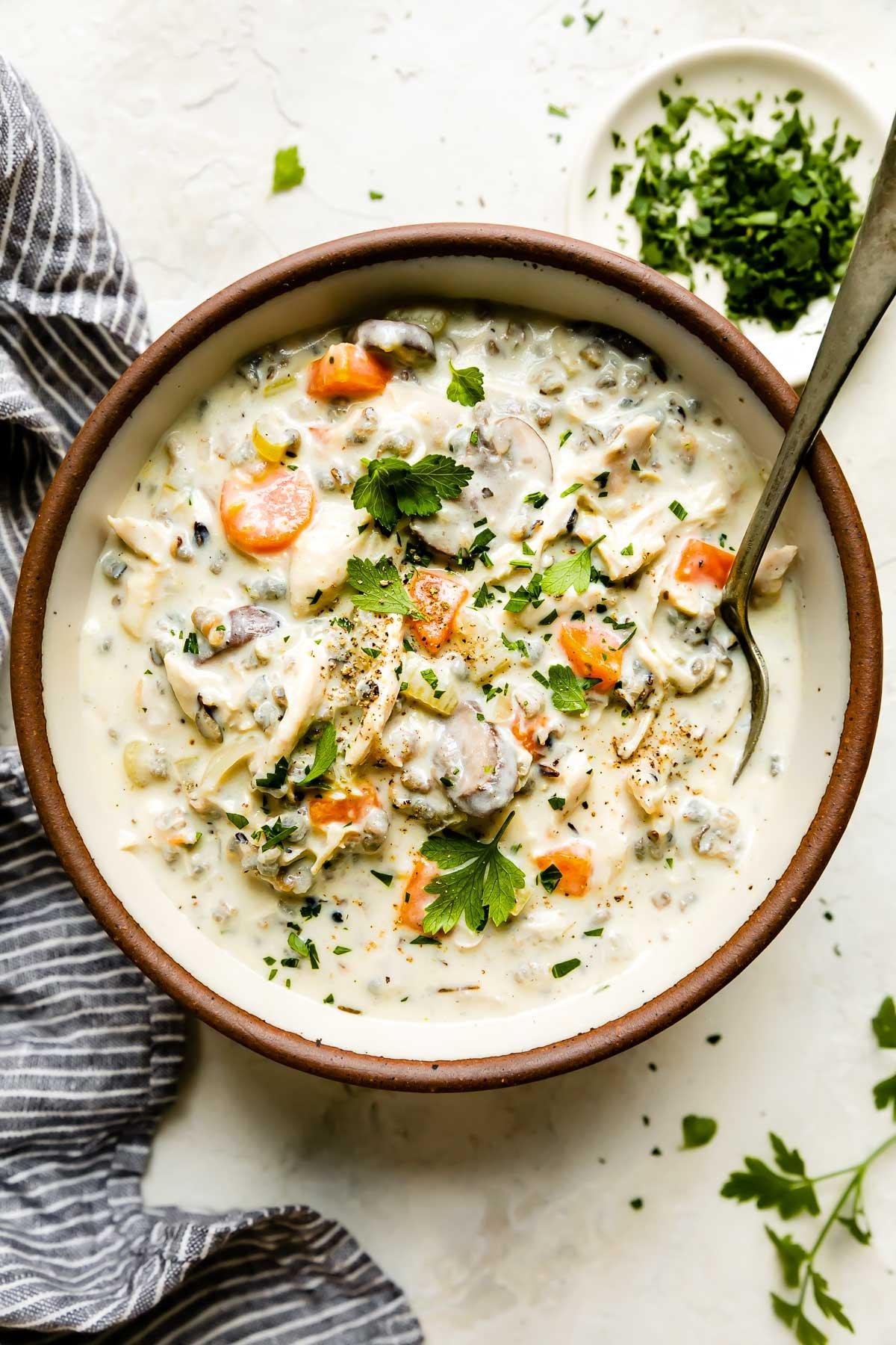 Close-up of ingredients for chicken and wild rice soup including chicken, wild rice, vegetables, and herbs