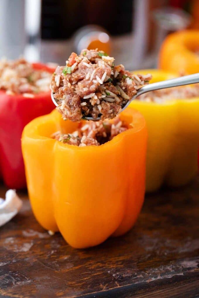 Close-up shot of someone preparing stuffed peppers in a kitchen, showcasing the filling and pepper preparation.