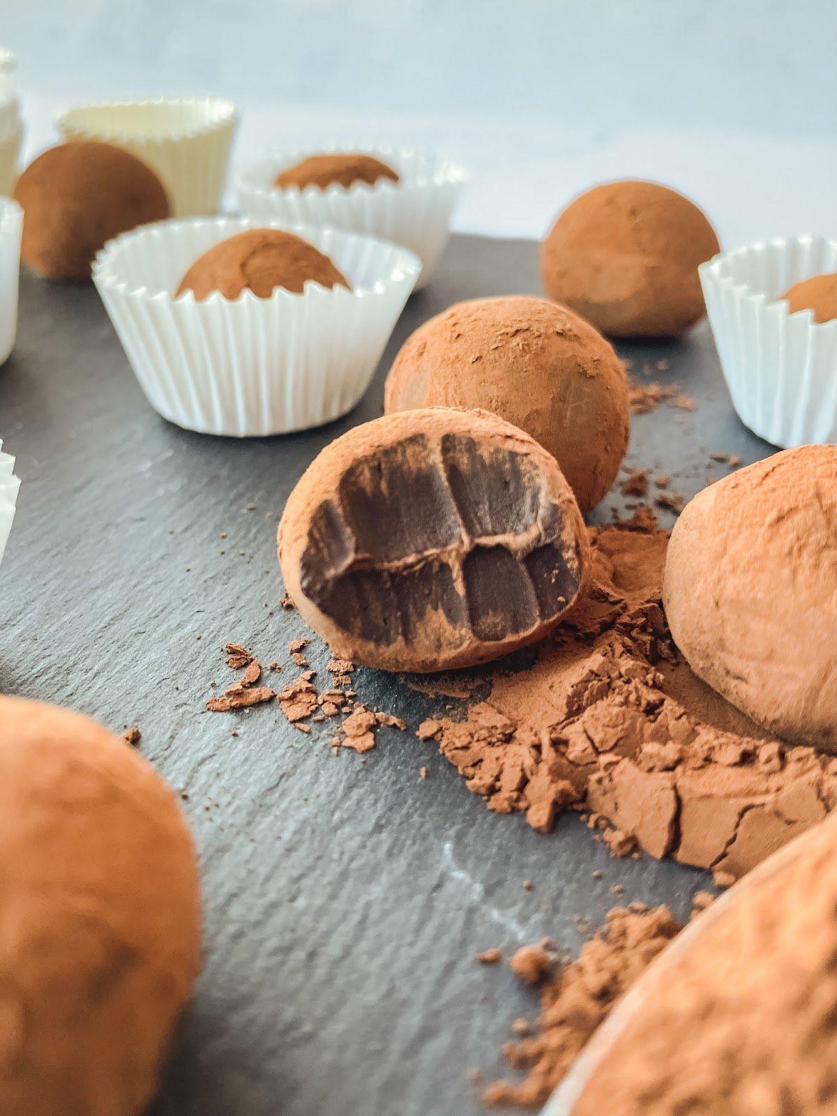 Close-up of homemade espresso truffles dusted with cocoa powder on a rustic wooden board, a small cup of espresso in the background