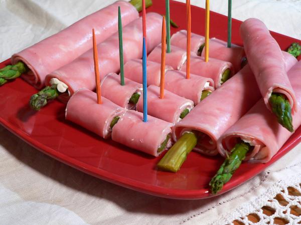 Close-up of a person assembling ham and asparagus spring rolls