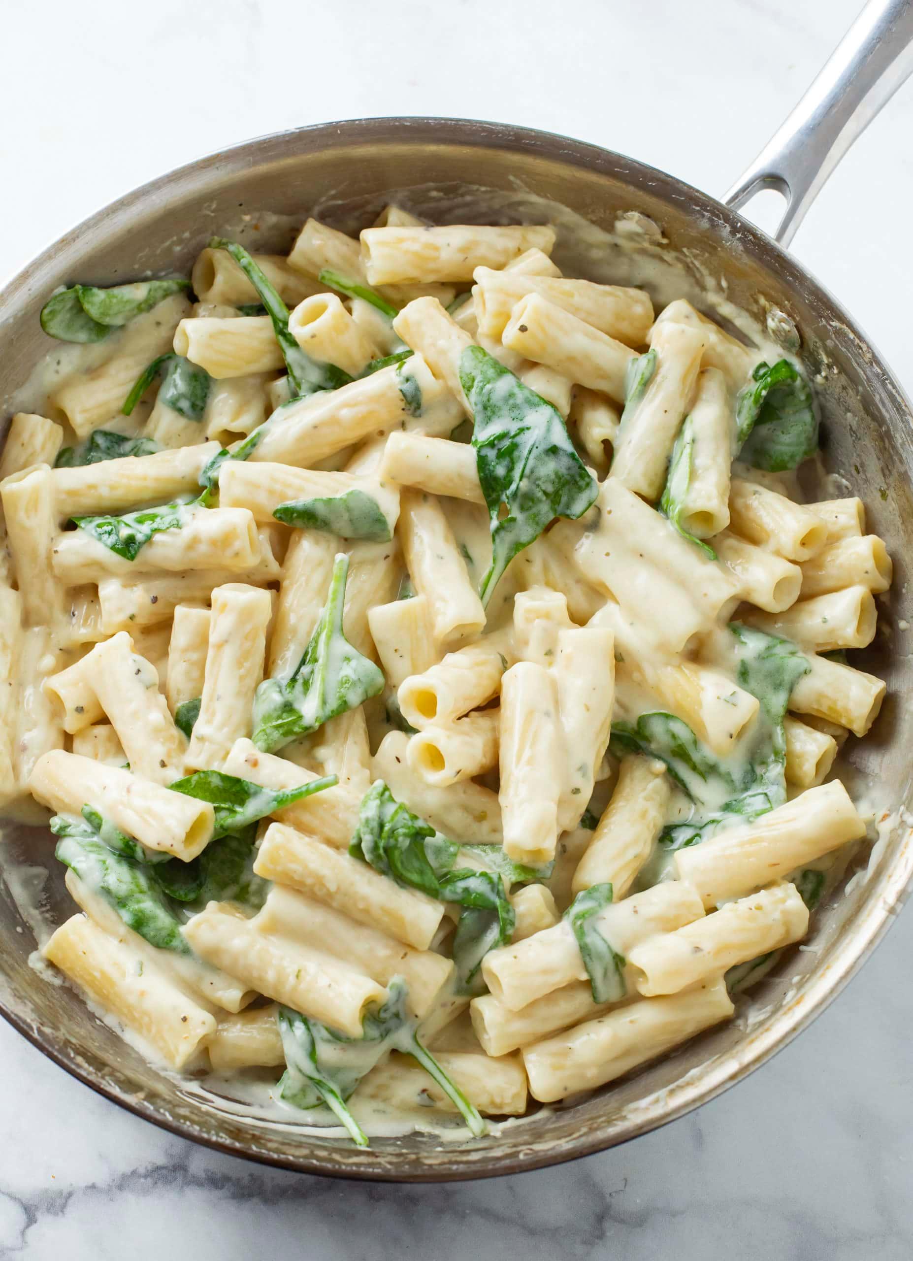 plate of creamy garlic spinach pasta with parmesan and fresh parsley, cozy kitchen setting