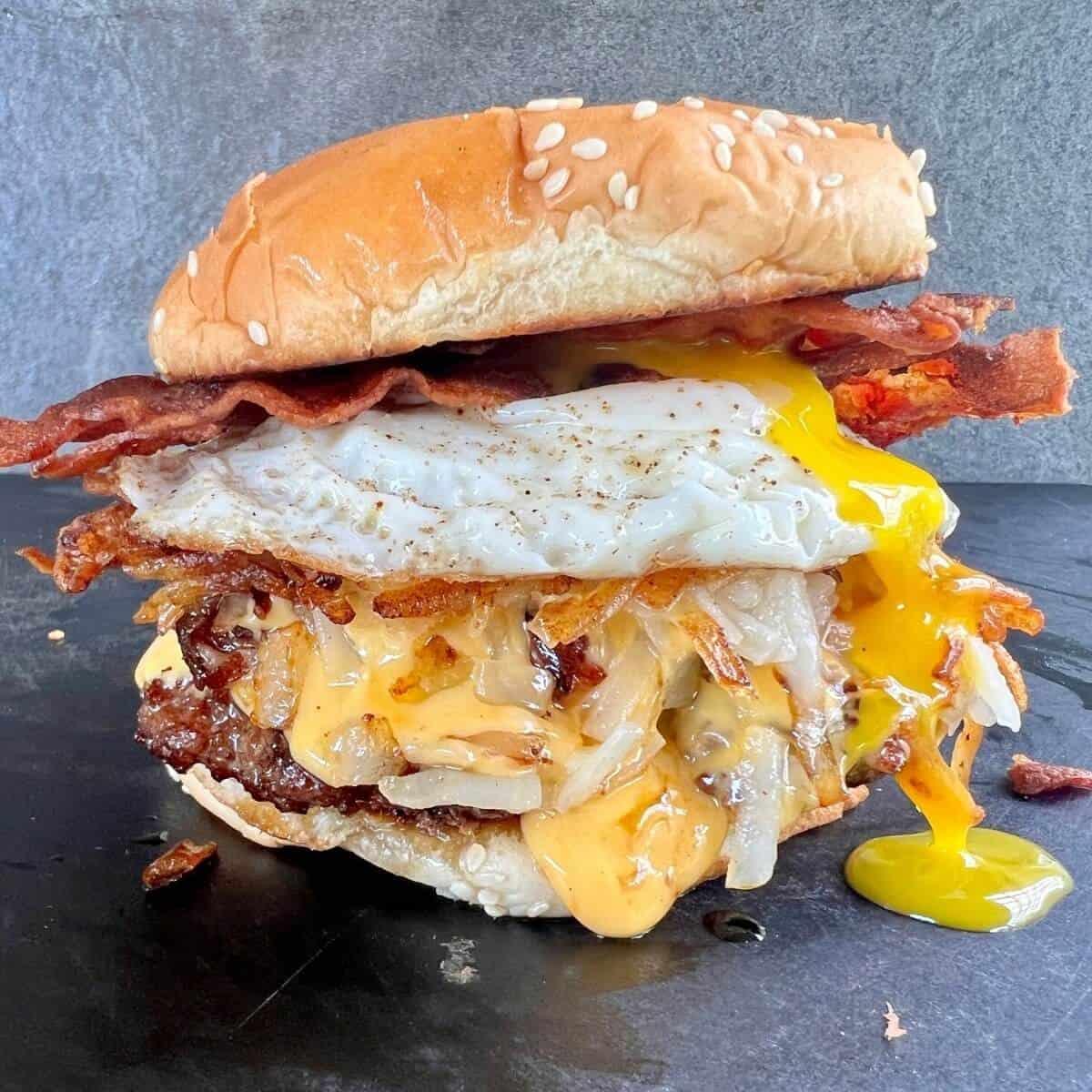 breakfast burger with egg and bacon on griddle