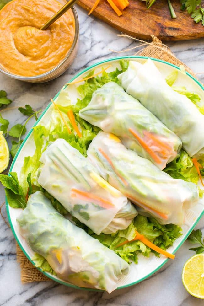 hands carefully assembling a chicken and avocado spring roll