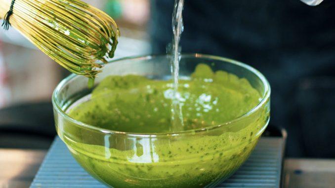 close-up of matcha powder being whisked into hot water