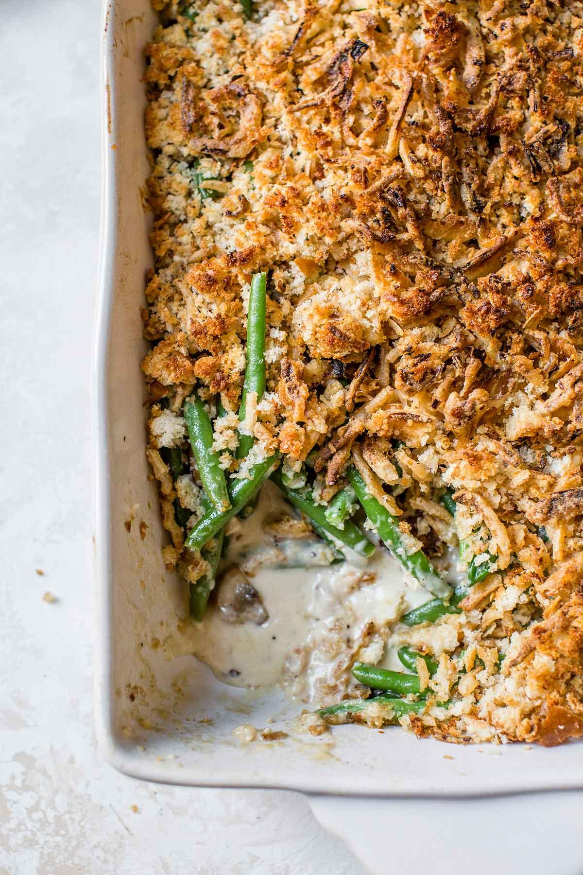 homemade green bean casserole with golden buttery crumb topping on a rustic holiday table