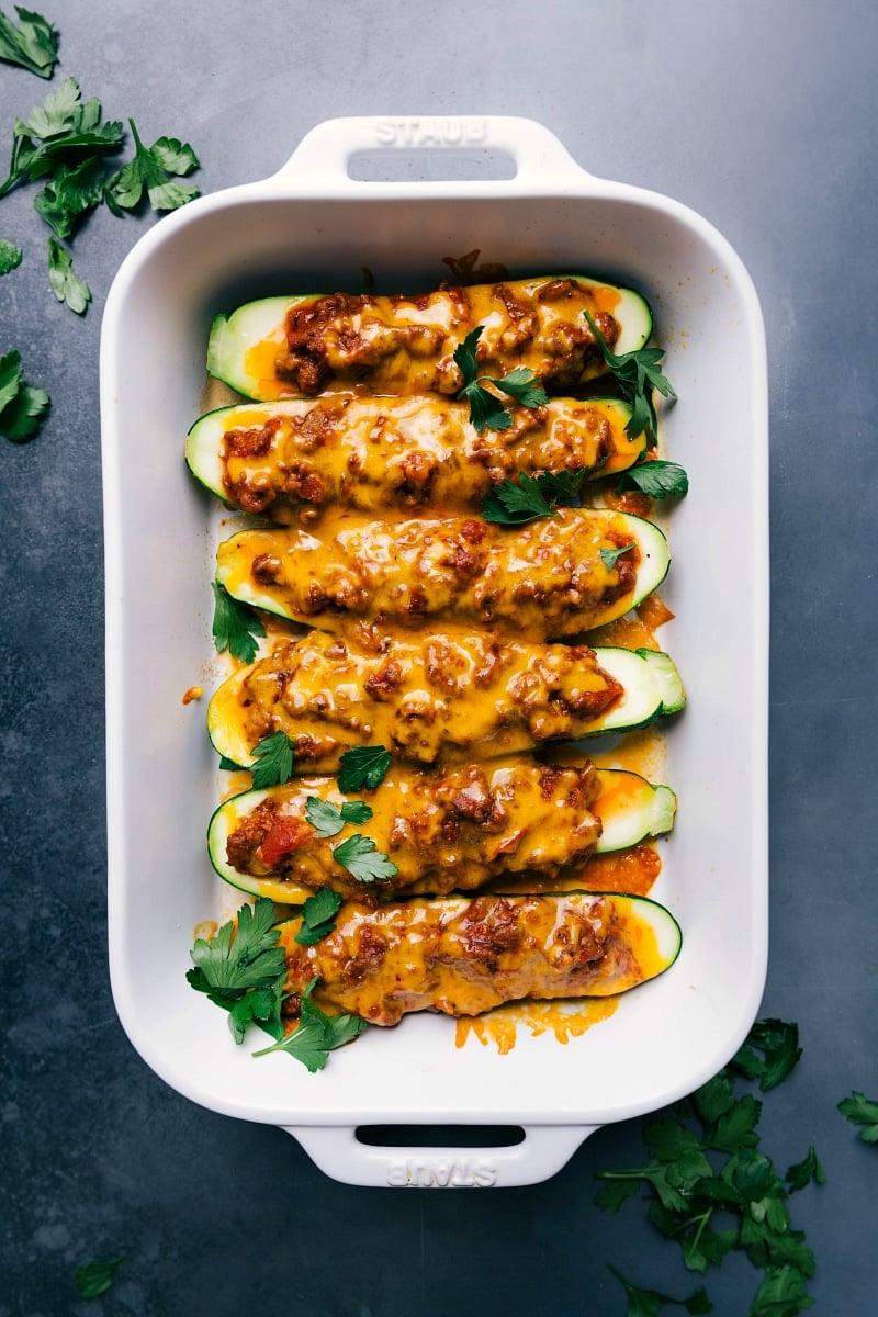 Overhead view of baked zucchini boats with melted cheese on top, garnished with fresh herbs