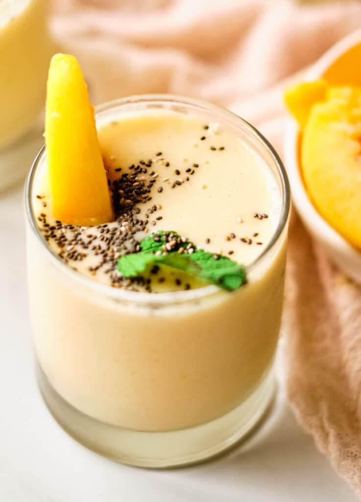 Finished smoothie in a glass, garnished with a slice of fruit and a sprinkle of chia seeds