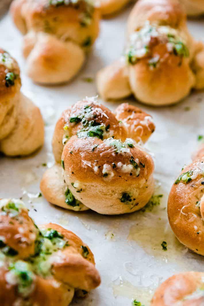 Homemade Parmesan garlic knots fresh out of oven, golden brown with melted cheese and fresh parsley
