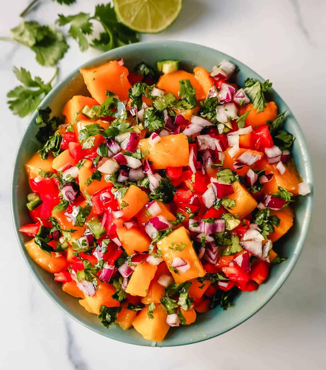 a colorful arrangement of fresh ingredients for mango salsa: ripe mangoes, red onion, cilantro, jalapeño, and lime