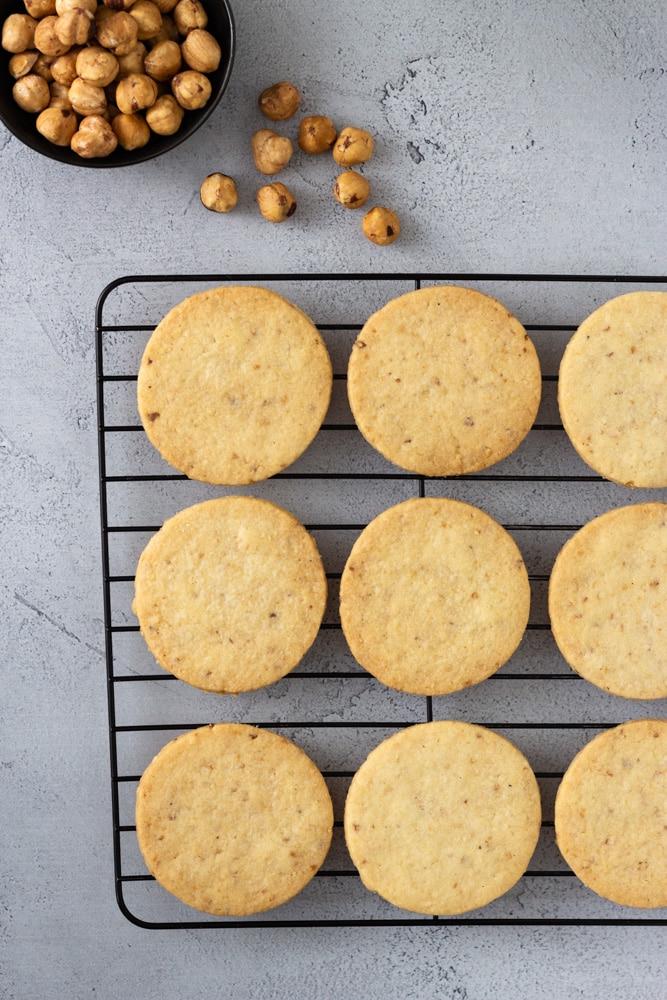 Overhead shot of freshly baked hazelnut cookies on a wire cooling rack, steamy and inviting
