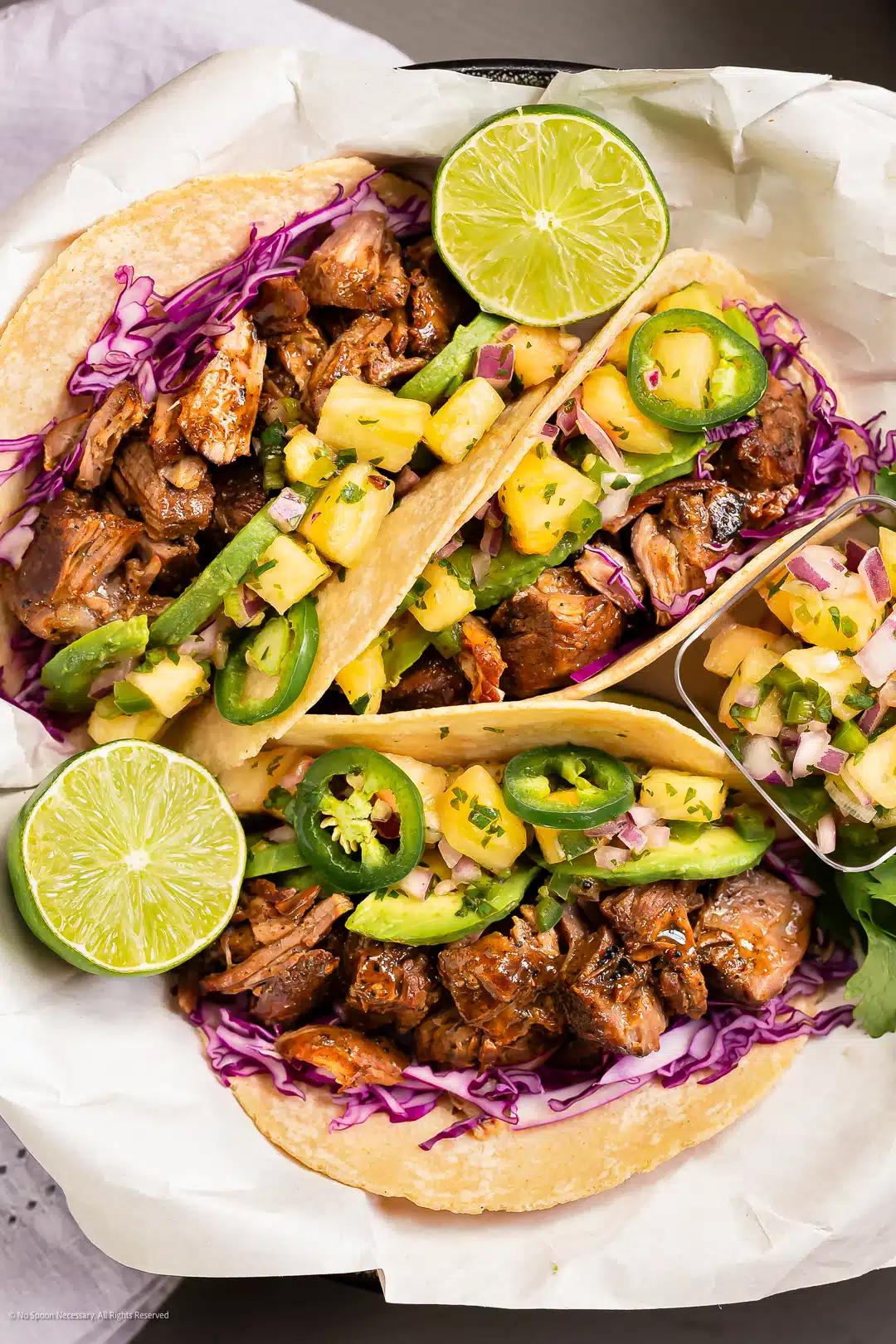 overhead shot of several Hawaiian pork tacos arranged on a platter with toppings
