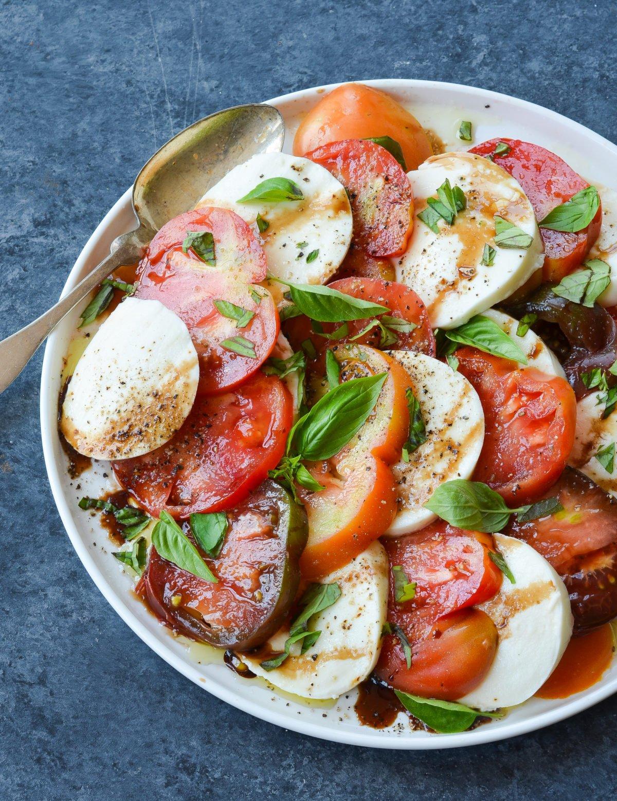 close up of caprese salad with black sea salt, basil, and balsamic glaze