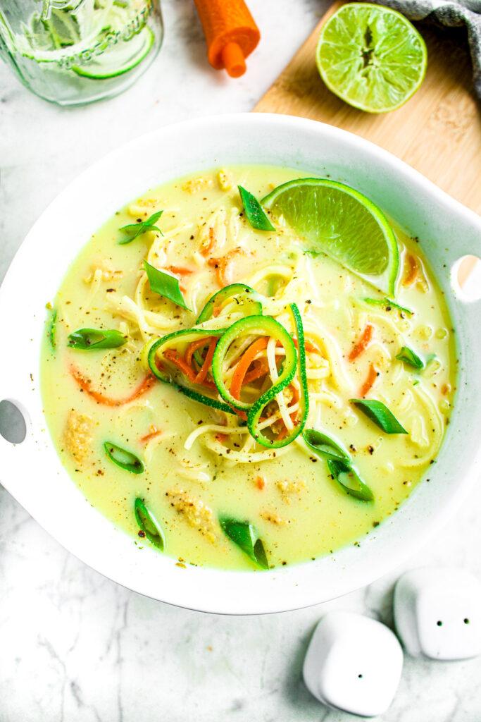 Overhead shot of a colorful bowl of spicy coconut zoodles with various toppings