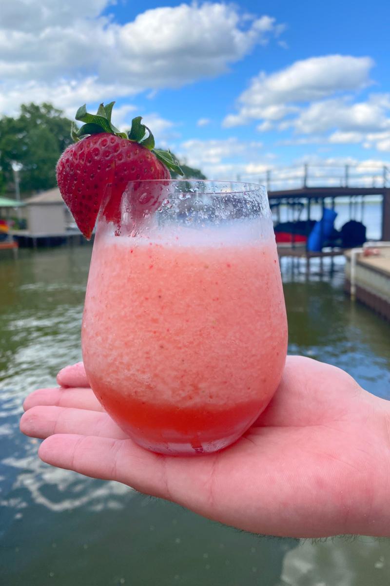close-up of a hand pouring a strawberry cinnamon smoothie into a glass