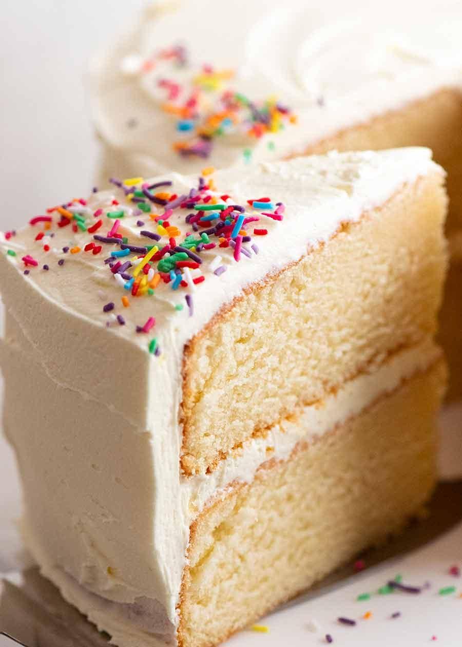 Close-up shot of a slice of vanilla cake with frosting and sprinkles