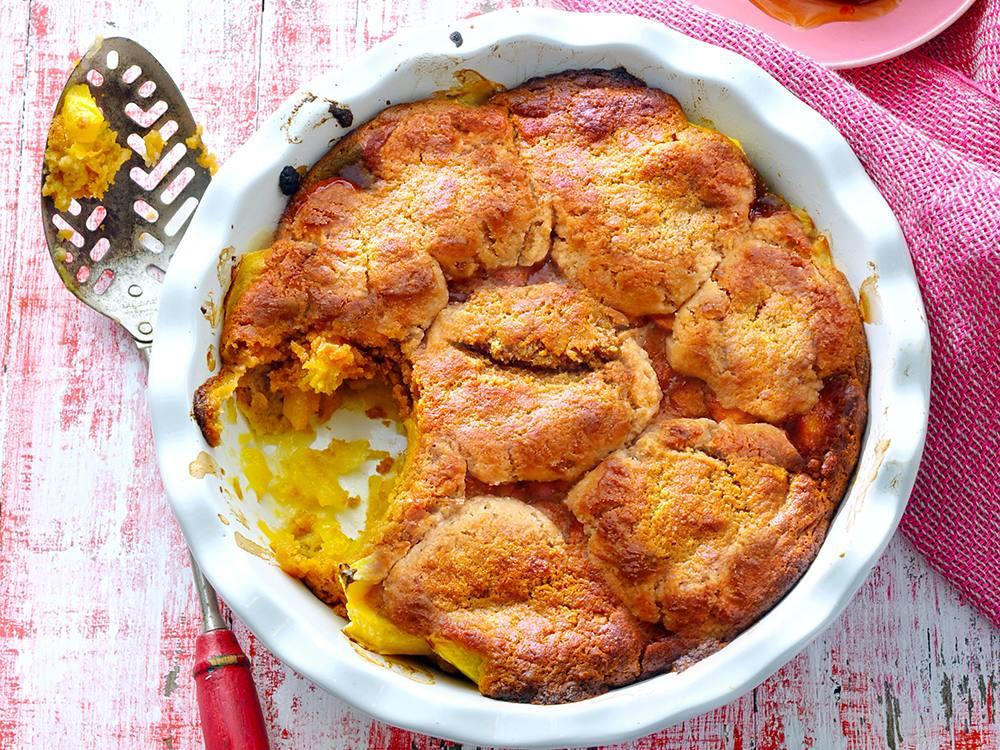 overhead shot of a freshly baked peach cobbler with cornmeal crust, steaming slightly