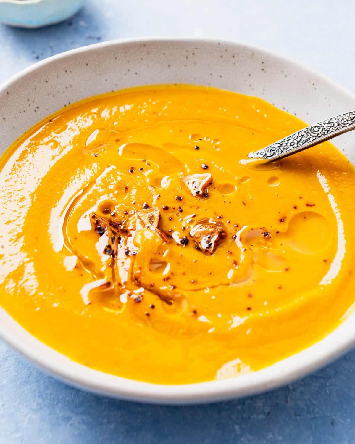 close up shot of blended pumpkin soup being poured into a bowl