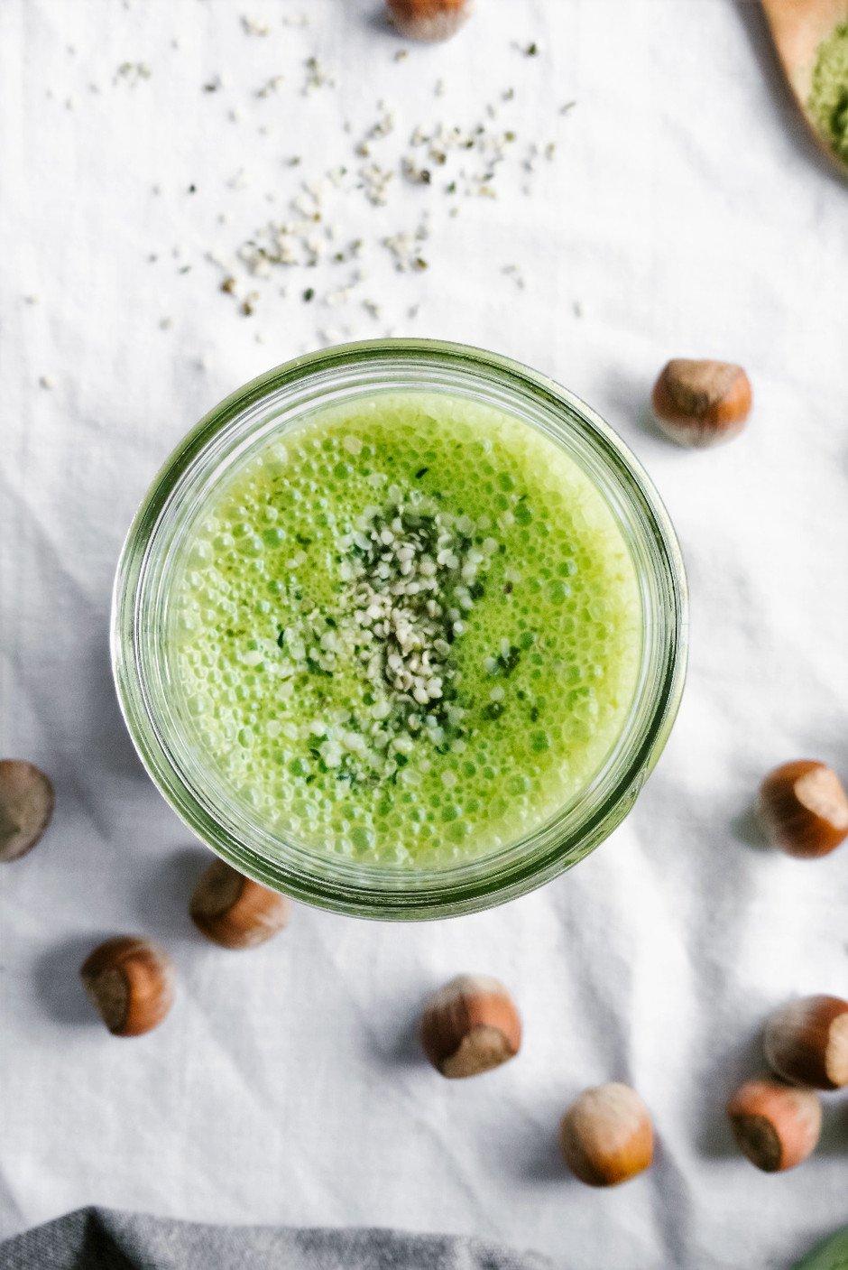 hazelnut matcha macchiato with visible layers in a glass cup, garnished with hazelnuts