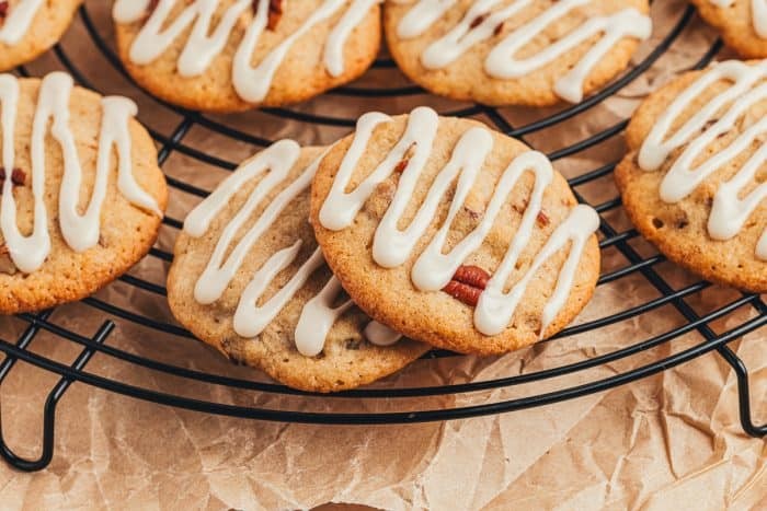 Close-up of freshly baked cocoa cookies with white drizzle on a cooling rack, warm lighting