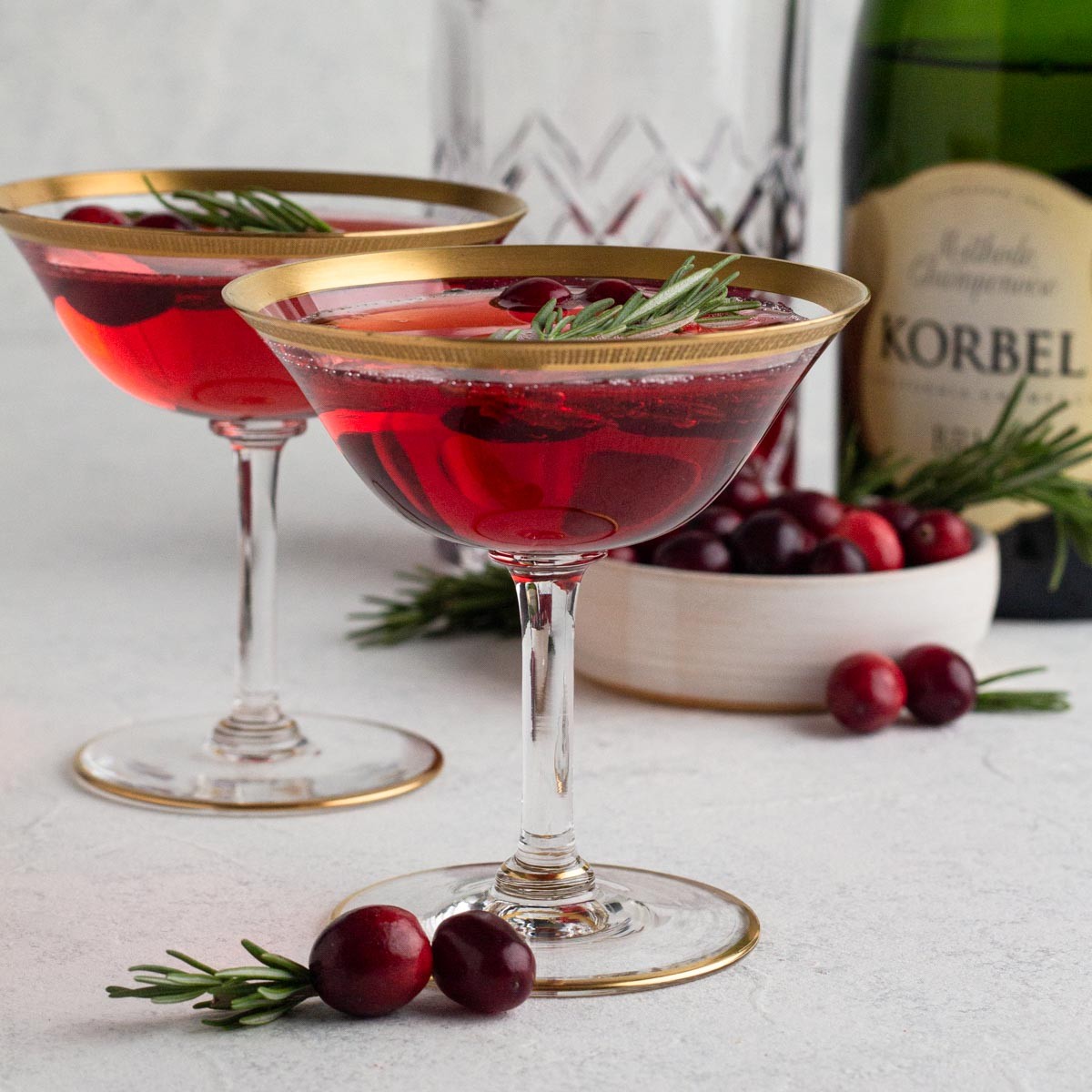 Elegant sparkling holiday mocktail in flute glasses with cranberry and rosemary garnish