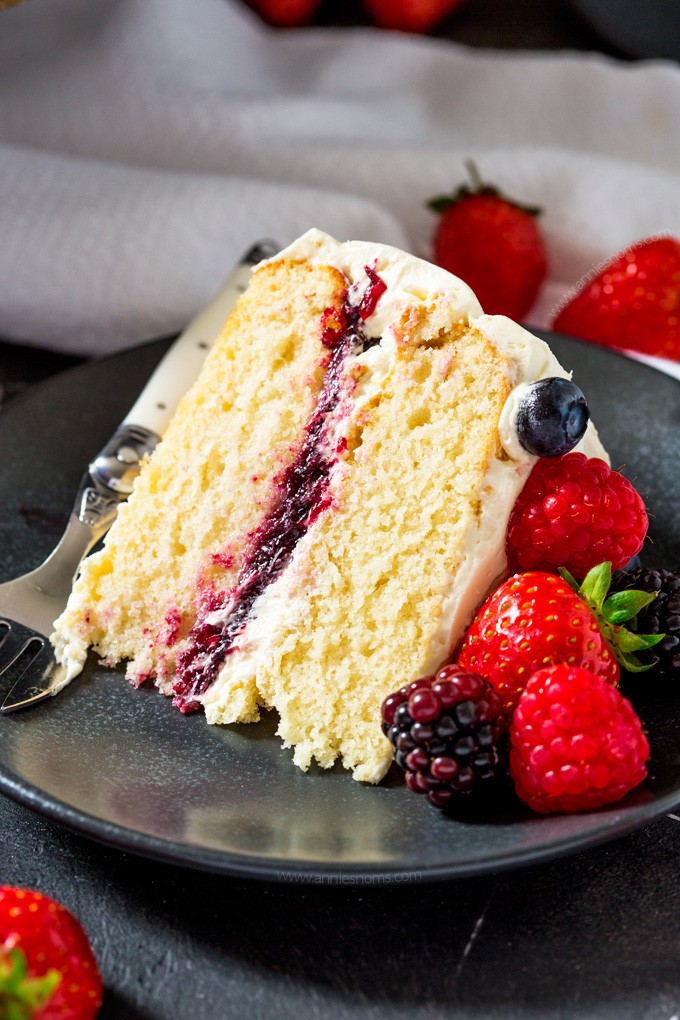 golden layer cake with vanilla frosting and fresh berries