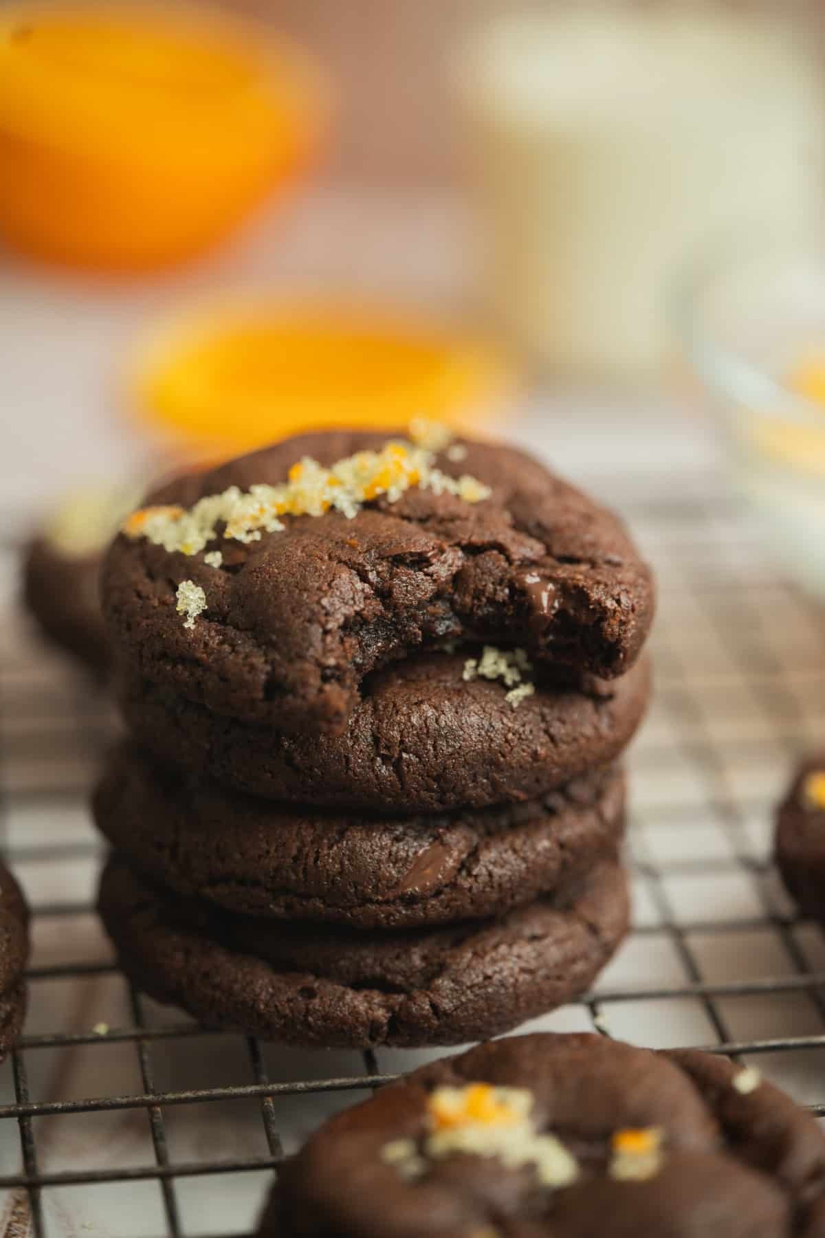 Glossy chocolate orange cookies stacked on a cooling rack, vibrant orange zest visible