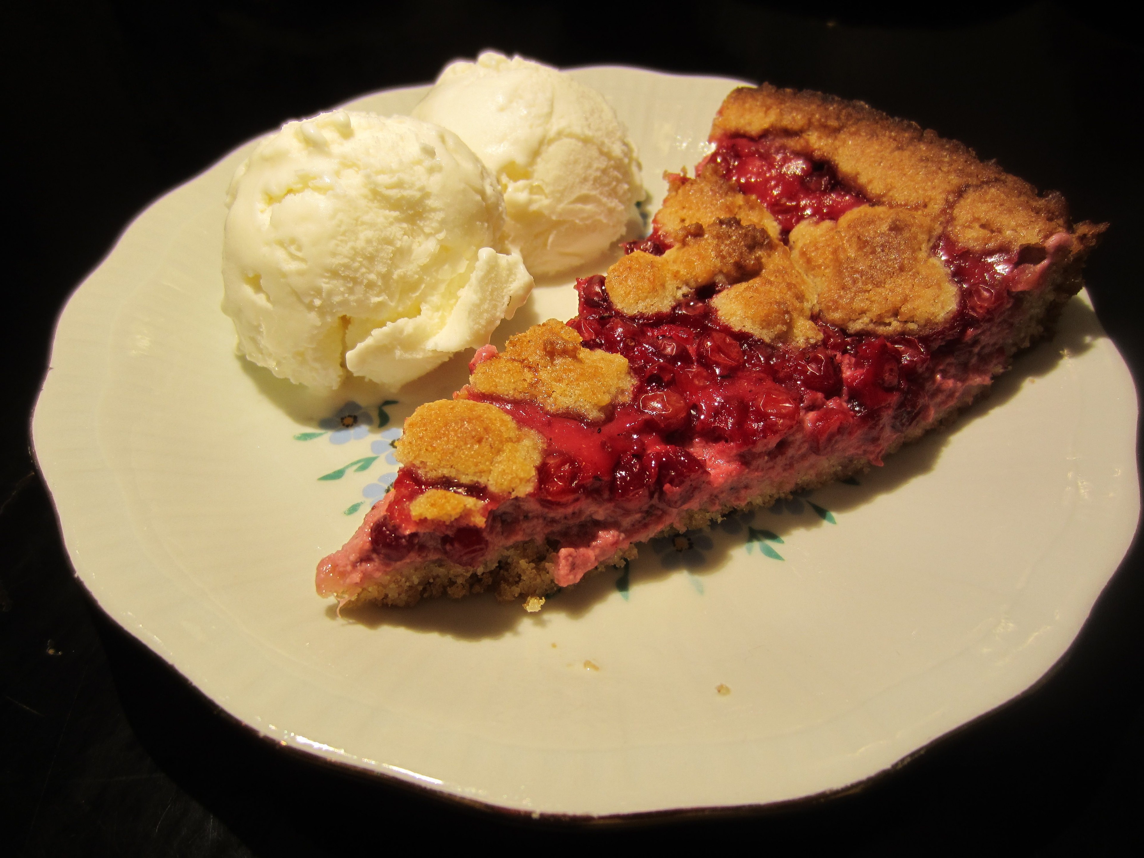 Lingonberry Ginger Tart on a wooden table, surrounded by fresh lingonberries and ginger