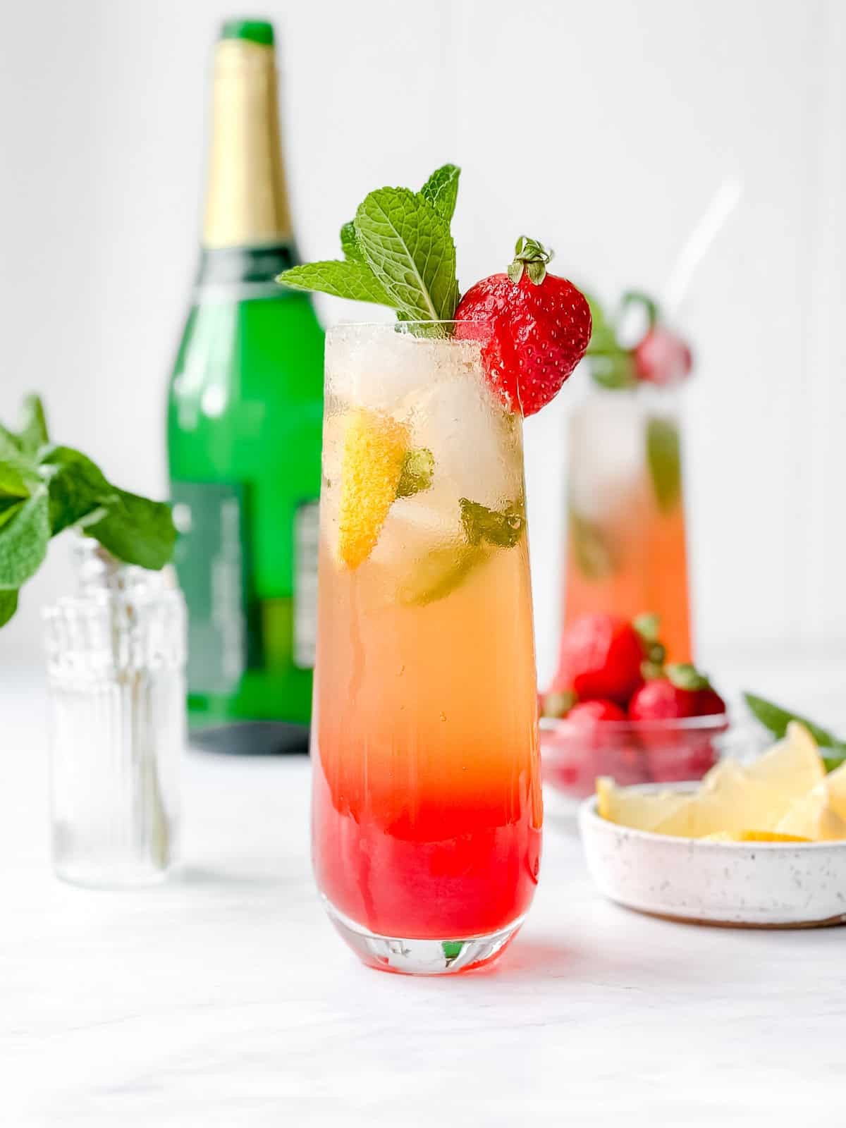 Festive non-alcoholic strawberry lemonade fizz in a tall glass, garnished with fresh strawberries, lemon slices, and a sprig of mint, on a cozy holiday setting.